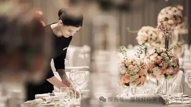 酒店服务员用粉红玫瑰、插花布置正式宴会桌